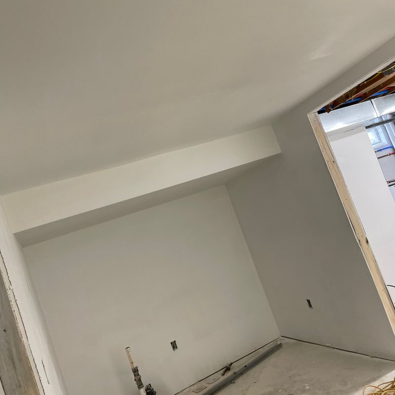 A basement room with fresh drywall and paint cans on the floor