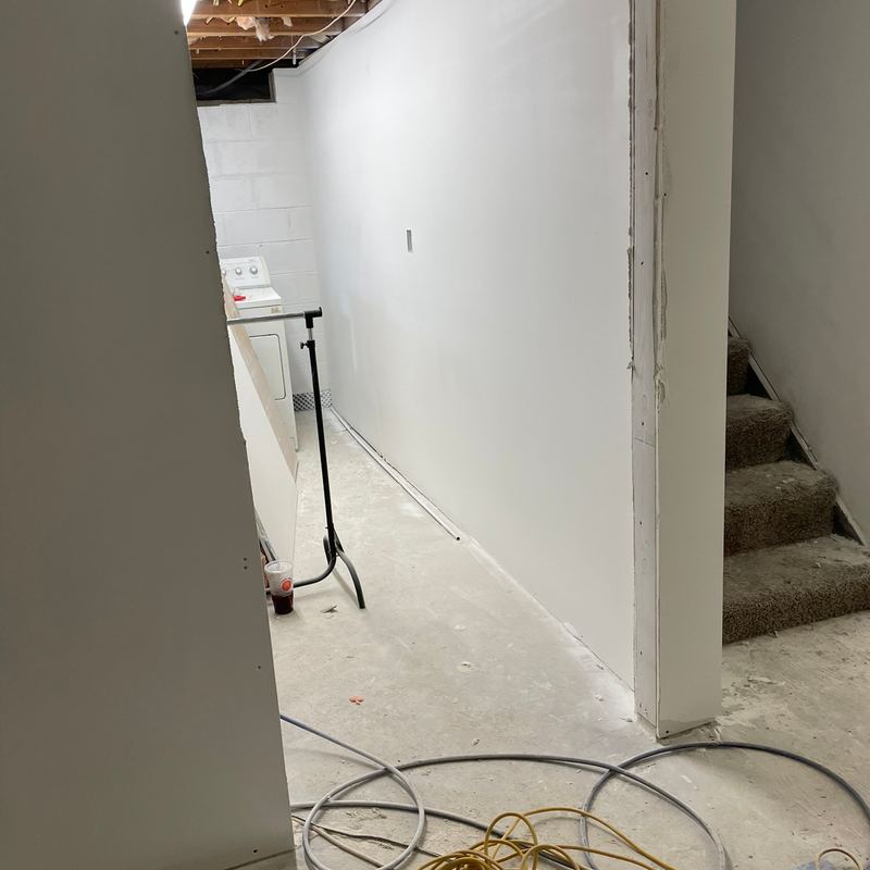 A newly walled basement hallway leading to carpeted stairs