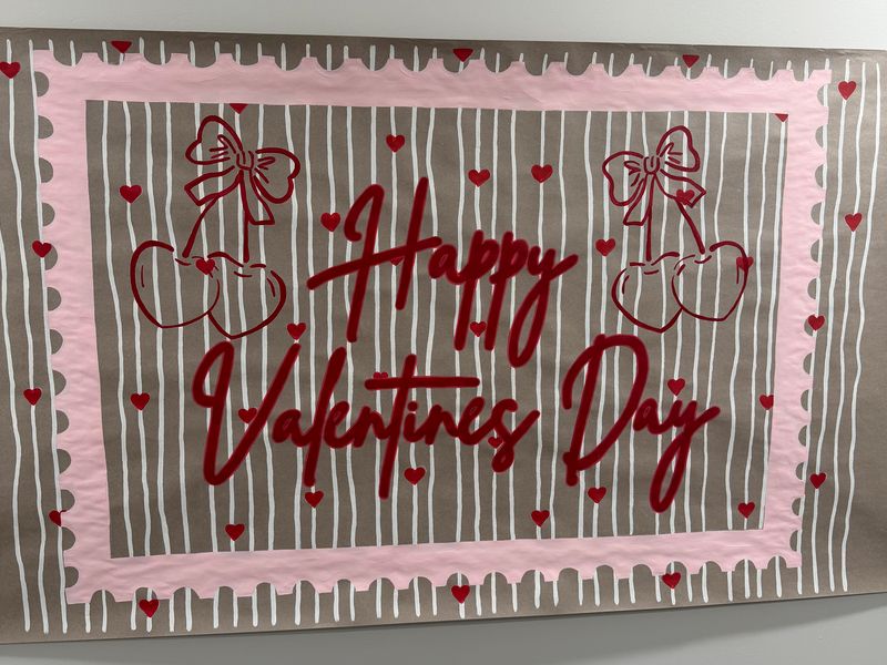 Handmade poster on kraft paper with pink borders, cherries and hearts, reading happy Valentine’s Day